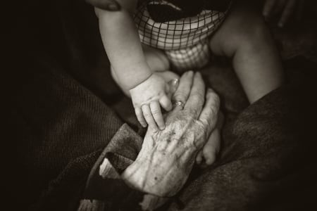 baby's hand touching old woman's hand